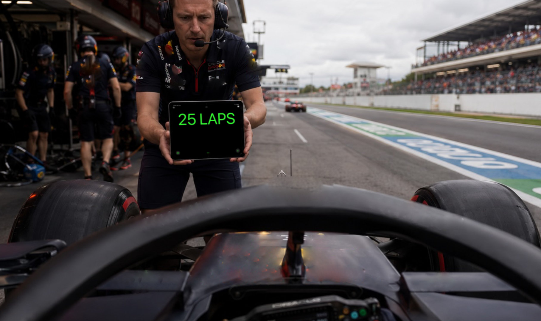 A Formula 1 crew chief holds dicto reading 25 laps as a pit board in the pit lane